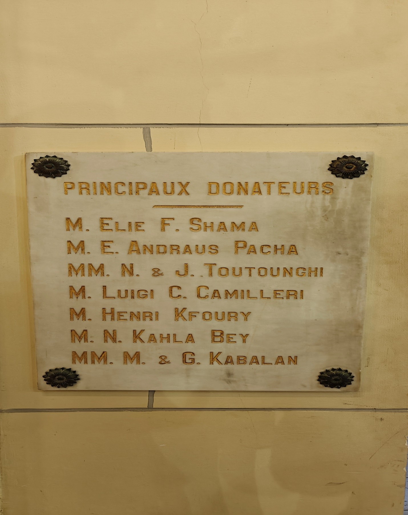 A plaque mounted on a wall, featuring engraved text and decorative elements.
